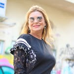 Elegant woman with blonde hair poses confidently against vibrant graffiti backdrop in Tel Aviv.